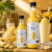 Banana dessert topping syrup bottles with banana ice cream, milkshake, and fresh bananas on a wooden table.