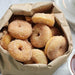 Classic Cake Donut Mix | World’s Best Tasting Donut Mix in a paper bag full of freshly made cinnamon donuts.