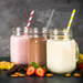 Three jars of thickshakes topped with caramel dessert topping, featuring strawberry and banana garnishes.