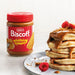Lotus Biscoff crunchy biscuit spread jar next to stacked pancakes topped with crunchy Biscoff spread and fresh raspberries