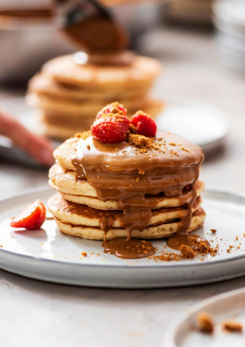 Fluffy pancakes drizzled with Lotus Biscoff spread 3kg and topped with fresh strawberries on a white plate