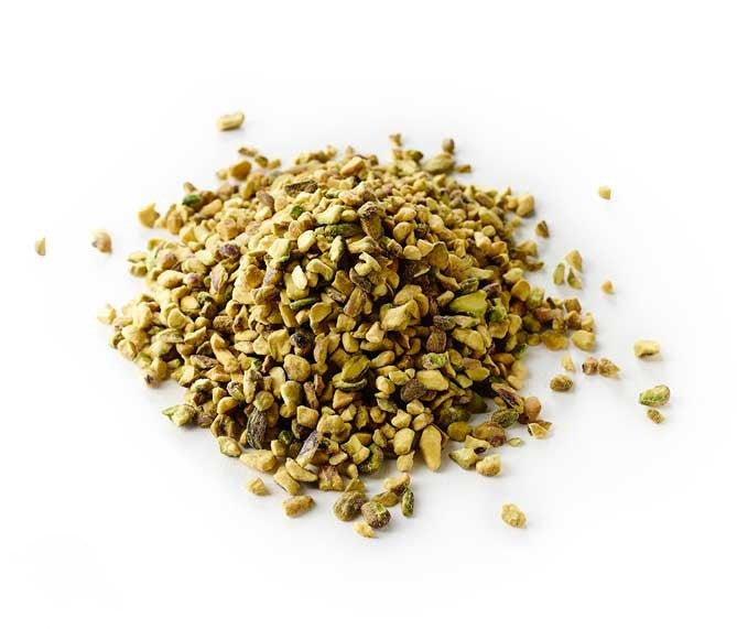 raw crushed pistachios bulk piled on white background, vibrant green crunchy pistachio pieces for baking and dessert toppings